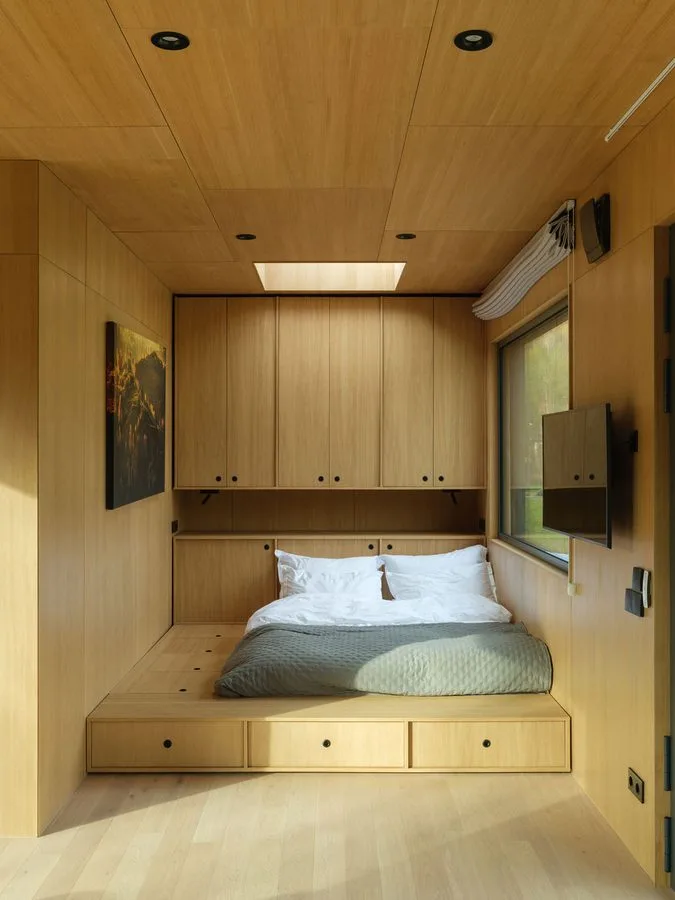Timber-clad sleeping nook with rooflight, storage under the bed platform and overhead cupboards