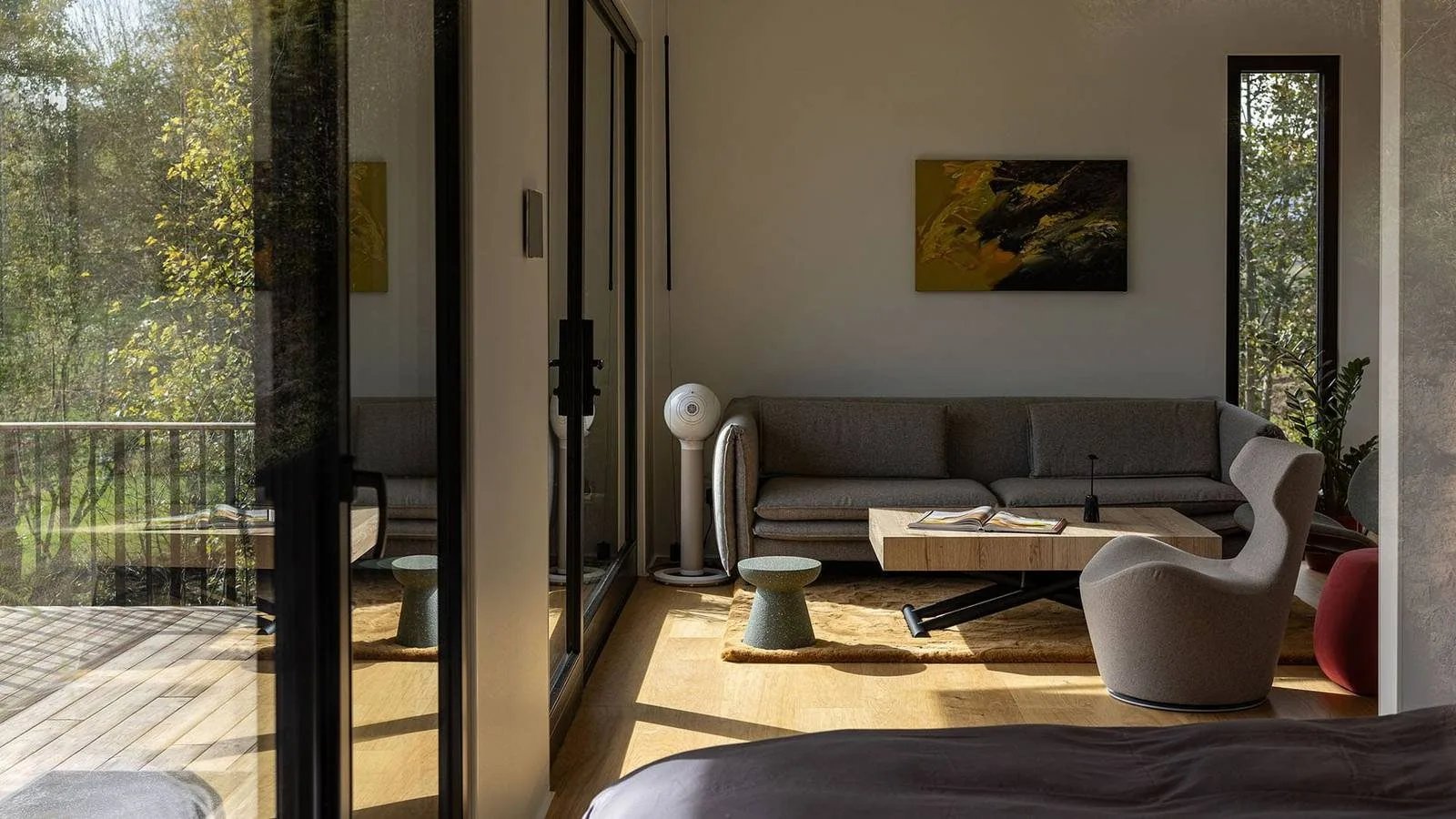 Blick durch die geöffnete Verglasung in den Schlafbereich des TR01 mit Bett und Kunst an der Wand