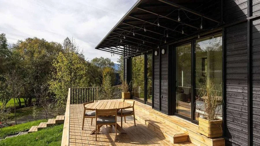 Terrace of the TR01 with round dining table and chairs, view across the meadow landscape