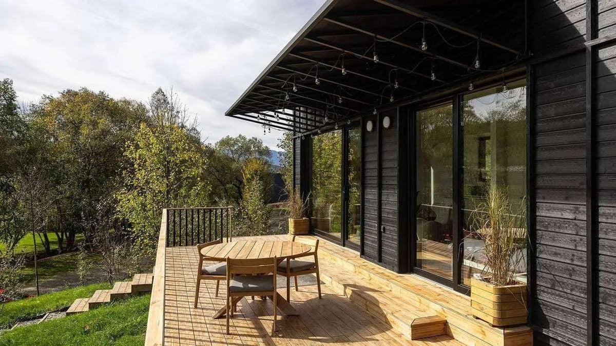 Terrasse des TR01 mit rundem Esstisch und Stühlen, Blick über die Wiesenlandschaft