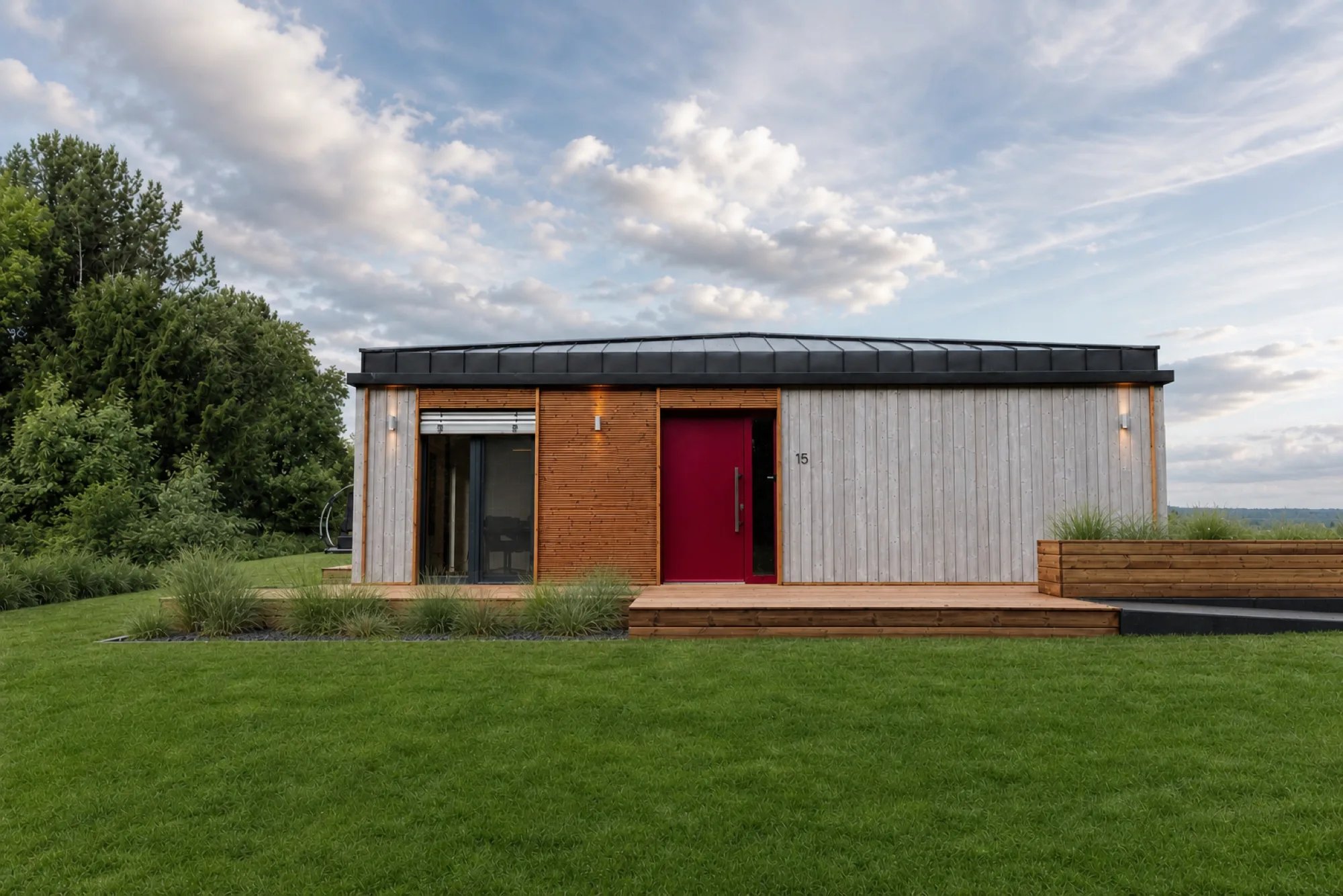 Gartenfassade des Musterhauses TR3M auf weiter Rasenfläche, rote Eingangstür, großer Himmel mit Wolken