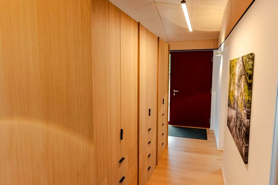 Hallway in the TR3M showhouse with full-height built-in oak wardrobes, view towards the dark red front door